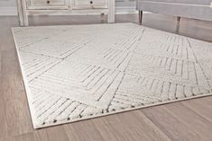 a large white rug on top of a wooden floor next to a dresser and bed