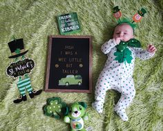 a baby is laying on a green blanket next to some toys and a sign that says irish i was a wee little bit taller