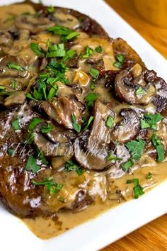 a white plate topped with meat covered in mushroom gravy and garnished with parsley