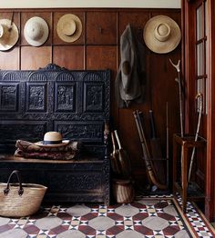 an old wooden bench with hats on the wall and other items in front of it