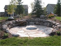 a stone fire pit surrounded by grass and rocks