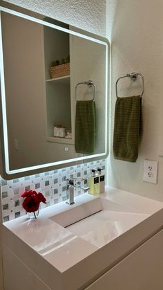 a bathroom sink under a large lighted mirror