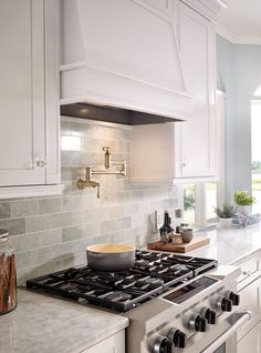 a stove top oven sitting inside of a kitchen next to white cabinets and counter tops