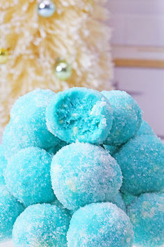 a pile of blue powdered donuts sitting next to a christmas tree