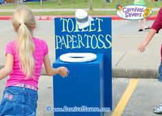 two children are playing with toilet paper on the sidewalk in front of a sign that says toilet paper toss