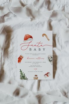 the baby announcement card is laying on top of some white sheets with red and green decorations