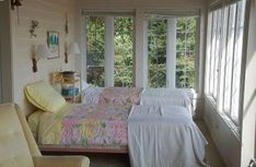 a bed sitting in a bedroom next to two windows with lots of light on them