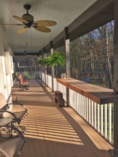 a porch with chairs and ceiling fans on the side of it in front of trees