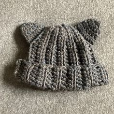 a knitted hat is laying on the floor with it's ears folded up