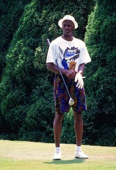 a man standing on top of a lush green field holding a golf racquet