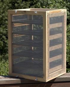 a large wooden box sitting on top of a wooden table next to some grass and trees