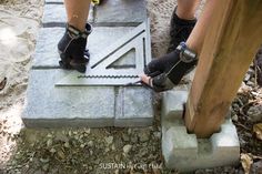 the legs of a person working on a cement slab with tools attached to it and two feet wearing work gloves