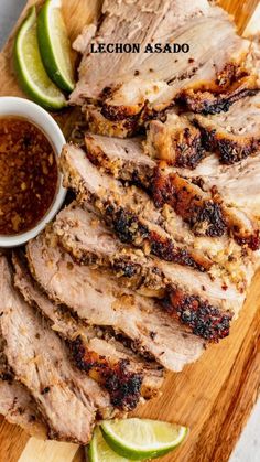 sliced pork with sauce and limes on a cutting board