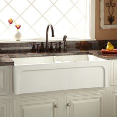 a white kitchen sink sitting under a window next to a faucet and counter top