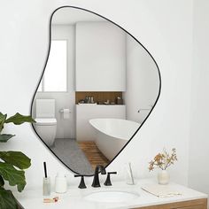 a bathroom with a large mirror on the wall and a plant in front of it