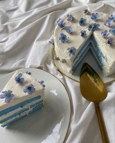 a blue and white cake sitting on top of a plate next to a knife with a slice cut out