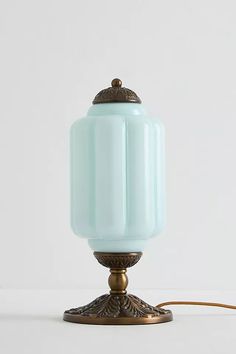 a light blue glass lamp on a metal stand with a cord attached to the base