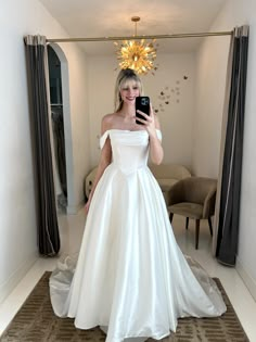 a woman in a white wedding dress taking a selfie