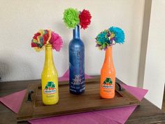 three colorful vases sitting on top of a wooden tray