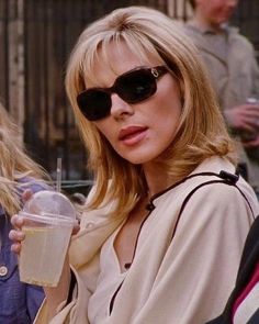 a woman wearing sunglasses and holding a drink