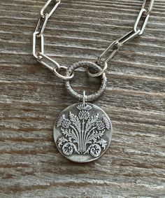 "This silver Scottish Thistle pendant is made from .999 fine silver. Fine silver has a higher silver content than sterling silver. The impression is from a wax seal stamp. It is 1\" diameter. The pendant is made from a wax seal stamp impression. Each pendant is made to order and each unique. This listing is for the pendant only." Silver Etched Necklace With Flower Pendant, Silver Necklace With Stamped Round Pendant, Silver Etched Coin Necklace, Silver Coin-shaped Etched Jewelry, Silver Etched Coin Jewelry, Silver Stamped Round Pendant Necklace, Silver Stamped Round Disc Jewelry, Stamped Silver Round Disc Jewelry, Silver Engraved Nature-inspired Necklace