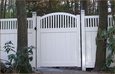 a white gate in front of some trees