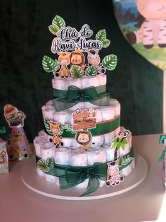 a baby shower cake made out of diapers with animals on it and green ribbon