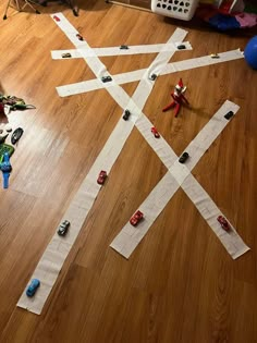 toy cars are lined up on the floor next to construction paper strips that look like roads