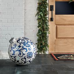 a blue and white ball ornament sitting on the ground in front of a door