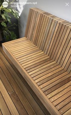 a wooden bench sitting on top of a hard wood floor next to a potted plant