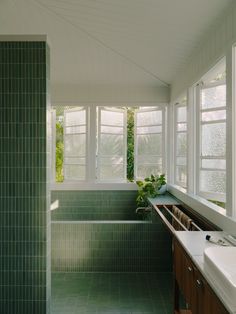 a bathroom with green tile walls and flooring next to a bathtub in the corner