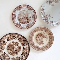 three plates with brown designs on them sitting next to each other