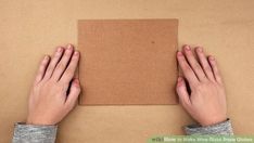 two hands on top of a piece of cardboard