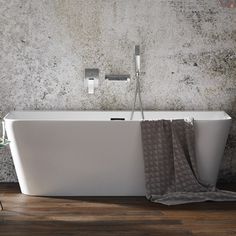 a white bath tub sitting on top of a wooden floor next to a shower head