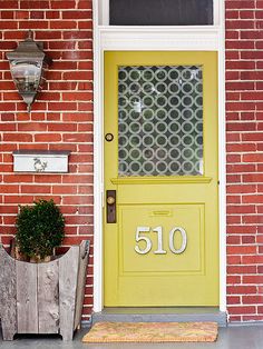 a yellow door with the number 50 on it is next to a red brick building