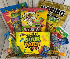 an assortment of snacks in a box on a wooden surface with the words, sour patch kids