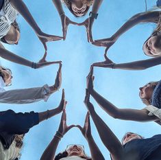 a group of people standing in a circle with their hands together and looking up at the sky