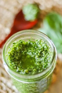 a jar filled with green pesto sitting on top of a table