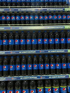 several rows of soda bottles on display in a store