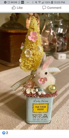 a tin can with some flowers in it and a stuffed animal inside the jar is sitting on a table