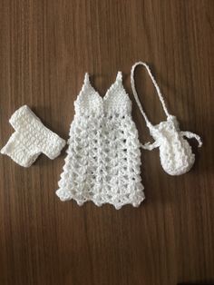 a crocheted baby outfit and booties are laying on a wooden table top