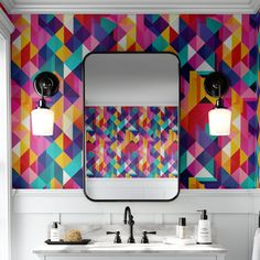 a bathroom with colorful wallpaper and two sinks in front of a mirror that has lights on it