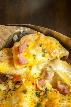 a wooden bowl filled with cheesy potatoes and ham