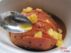 a bowl filled with meat and pineapples next to a spoon in the bowl