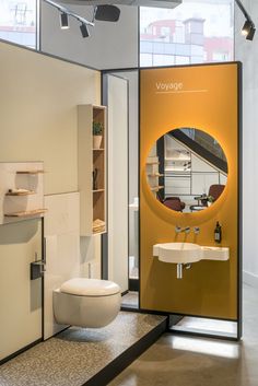 a bathroom with a toilet, sink and mirror in it's display area next to a window