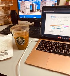 a laptop computer sitting on top of a desk next to a cup of coffee and a drink