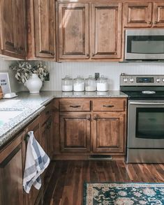 a kitchen with wooden cabinets and stainless steel stove top oven, dishwasher and microwave