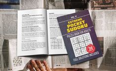 an open book with sudoku on top of it next to several other books and papers