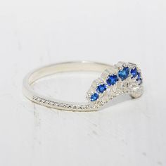 a white gold ring with blue sapphires and diamonds on the side, sitting on a table