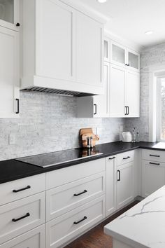 a kitchen with white cabinets and black counter tops is pictured in this image from the front view